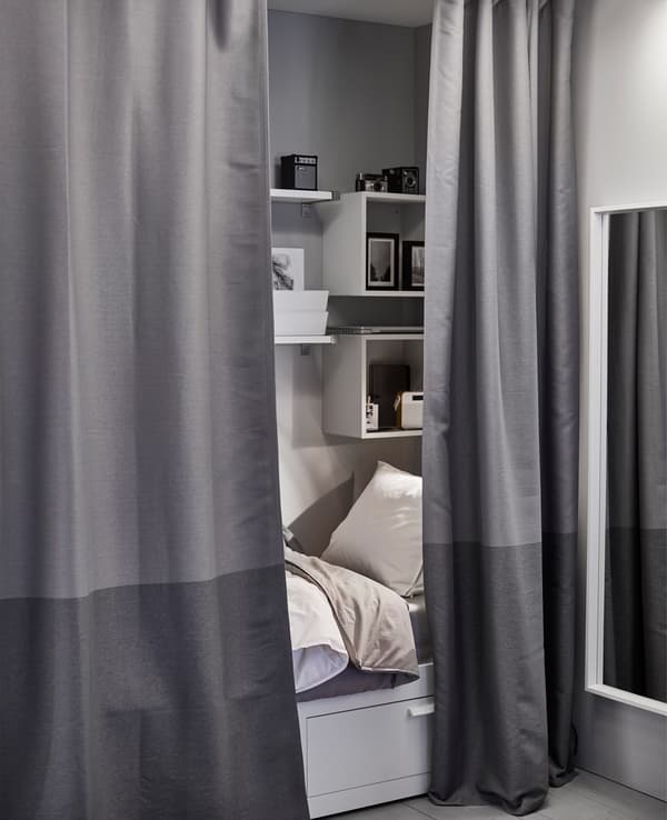 A small sleeping space getting extra privacy with dark grey curtains that work as a room divider.