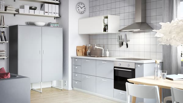 A small-space kitchen featuring cabinets with grey drawer fronts, a white wall cabinet and a grey wall cabinet with doors.