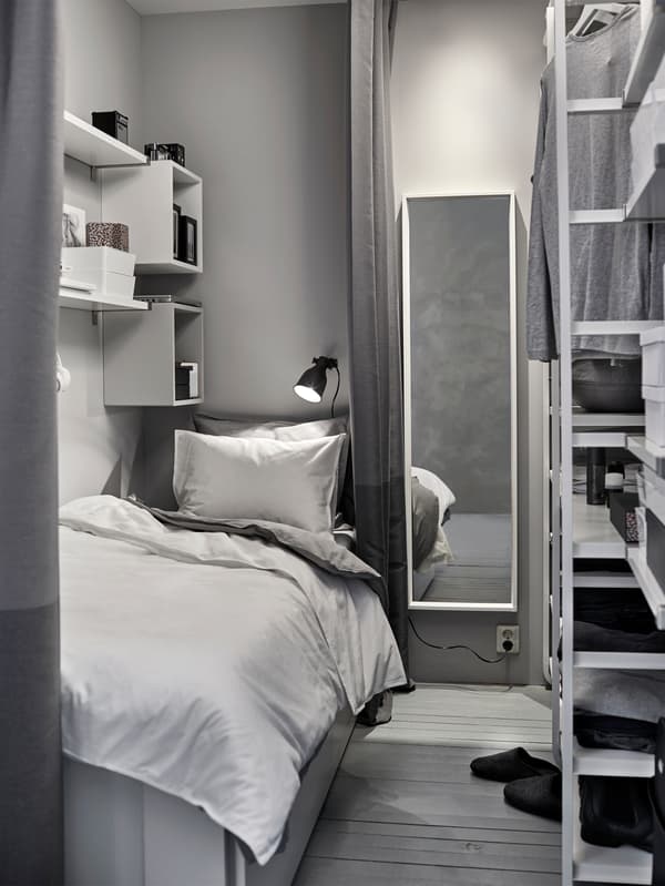 A small white and grey sleeping area in a shared space with a wardrobe.