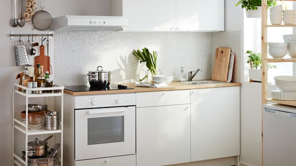 A small white kitchen consisting of a built-in oven and base cabinets, drawers, a worktop and a wall cabinet.