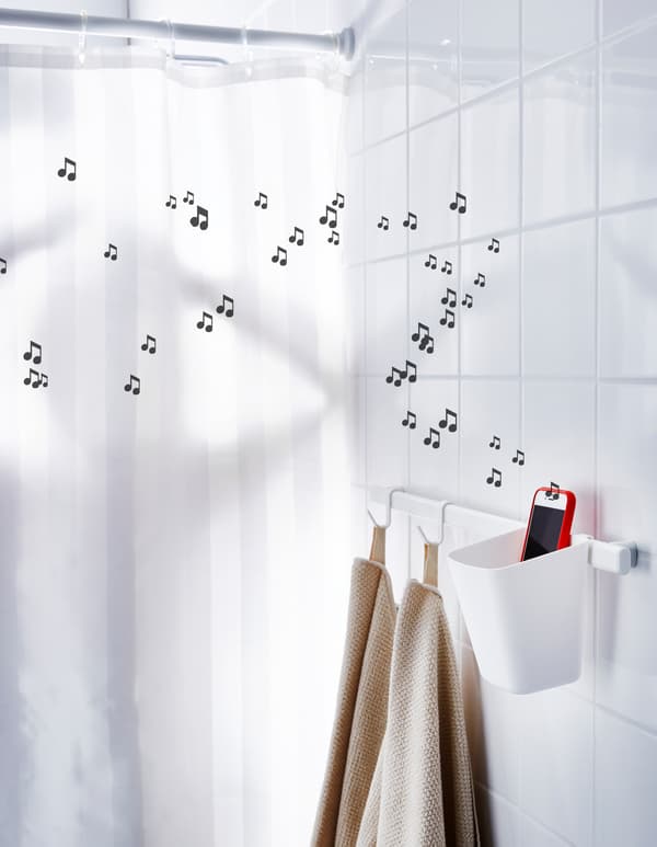 A smart phone playing music sits in a small plastic container next to a shower.