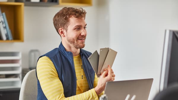 A smiling man in blue-and-yellow IKEA co-worker clothing, standing in a casual pose.