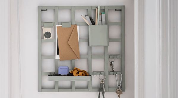 A SNICKRA 8-piece storage board set in gray-green mounted on a hallway wall.