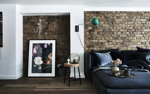 A sofa against an exposed brick wall.