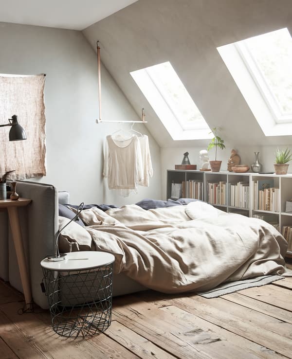 A sofa bed is extended and made up with neutral coloured bed linens.