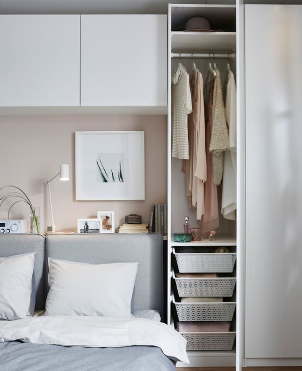 A sofa bed is made up for sleeping, and the storage next to it is opened to reveal clothes within.