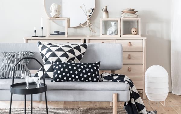 A sofa in a light and bright living room with bold patterned black and white cushions.