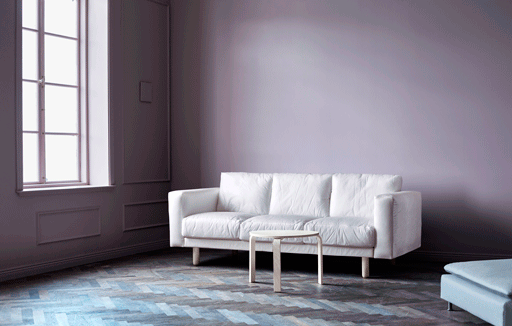 A sofa in a living room with pink walls.
