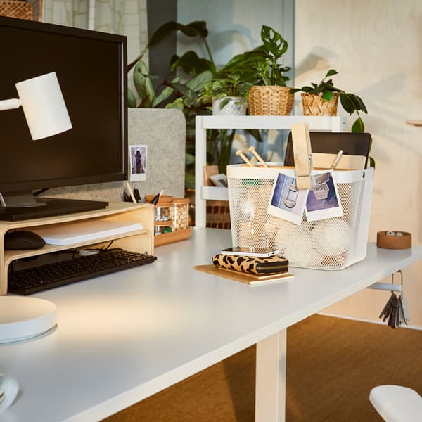 A softly sunlit office with a TROTTEN sit-stand desk fitted with a VATTENKAR laptop stand and a VATTENKAR desktop shelf.