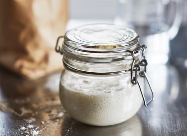 A sourdough starter mixture comes together in a glass jar.