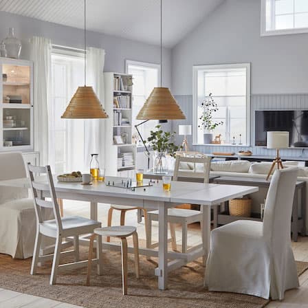 A spacious and bright dining room with a connected living room. The dining table is extended, and stools provide more seats.