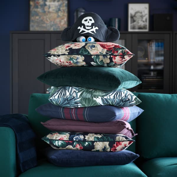 A stack of colourful cushions on a VIMLE sofa, with a pirate hat perched on top.