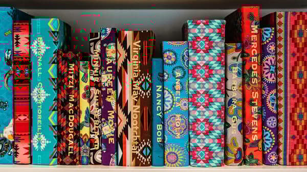 A stack of fabric wrapped books with gold names printed on the spines.