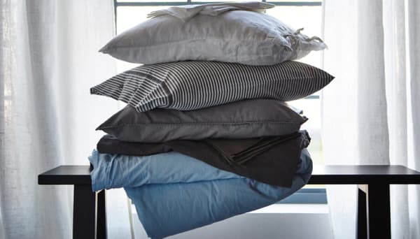 A stack of pillows and bed textiles in different materials that help regulate sleep temperature
