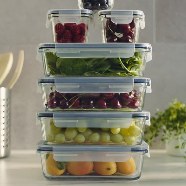 A stack of several food containers of different-sizes, with fruits and vegetables inside.
