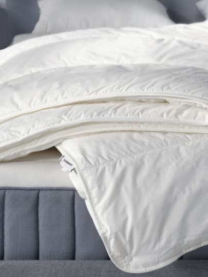 a stack of white duvets on top of a mattress