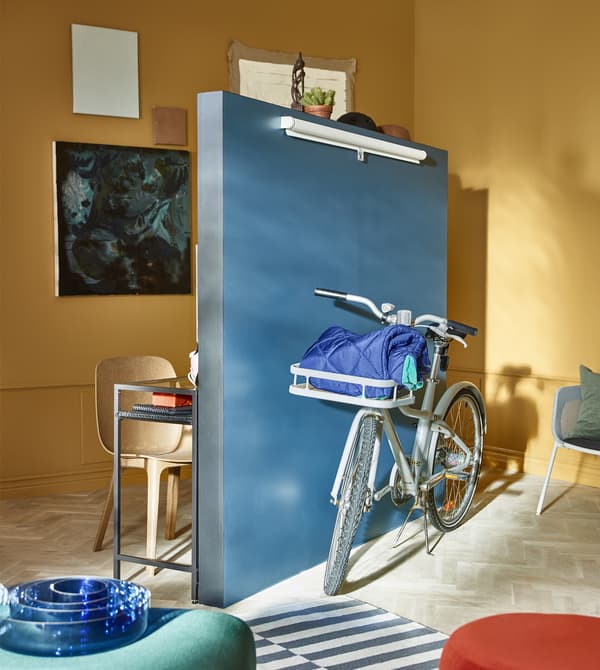 A stand-alone wall sits in the middle of a living room, with a bicycle placed in front of it.