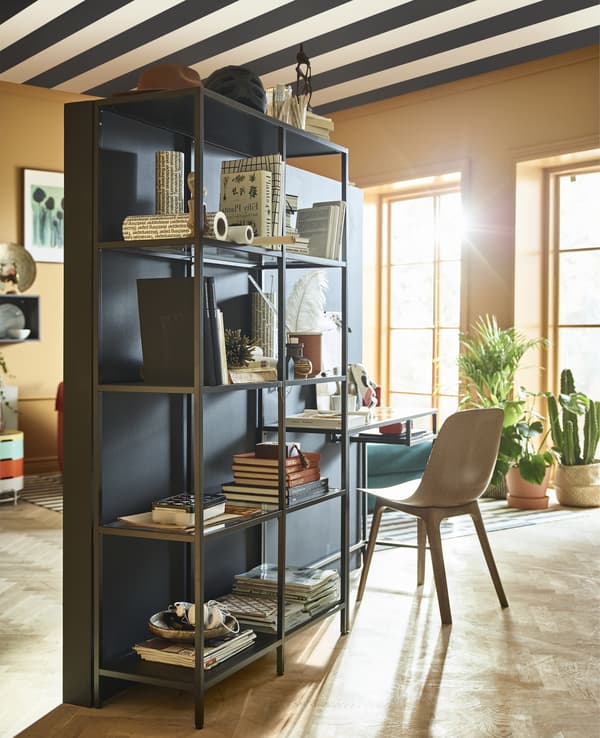 A stand-alone wall with a workspace sits in teh middle of a living room.