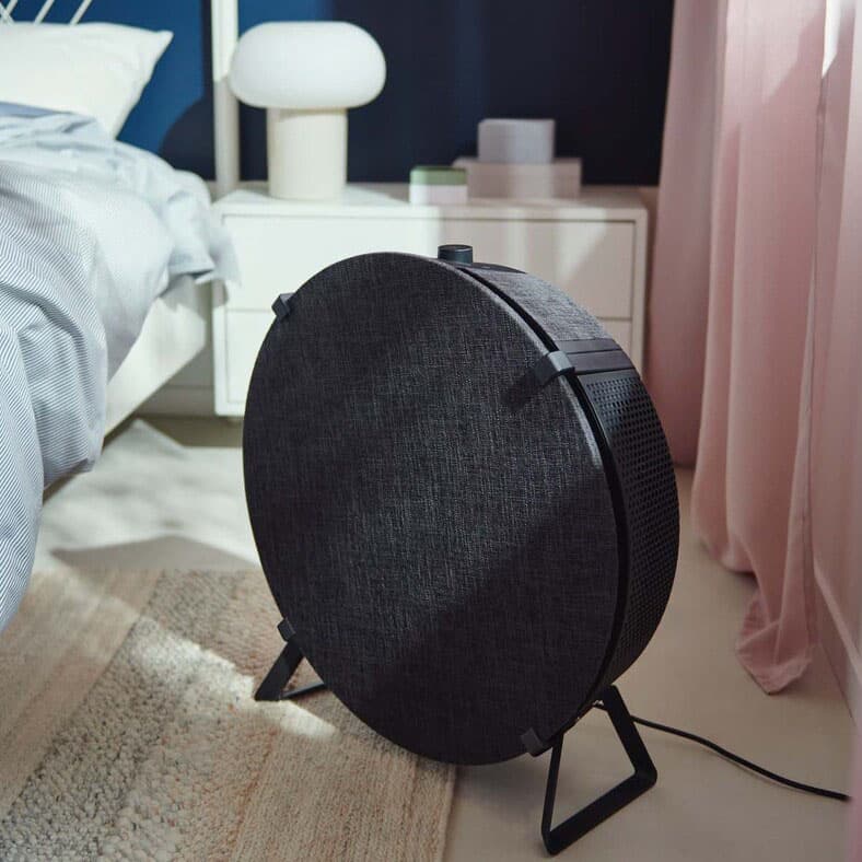 A STARKVIND air purifier standing on a floor of brightly-lit bedroom.