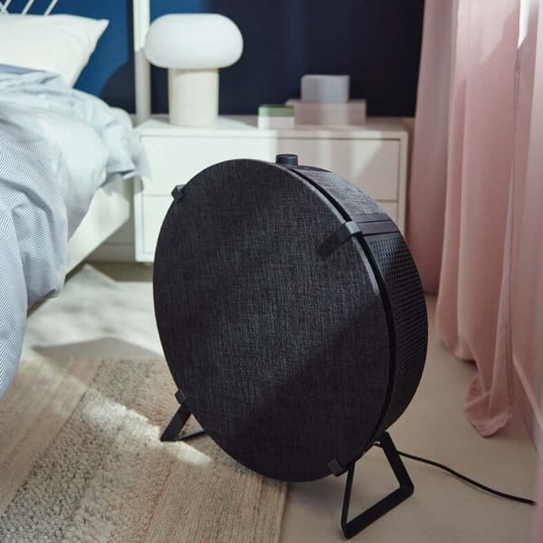 A STARKVIND air purifier standing on a floor of brightly-lit bedroom.