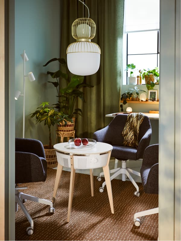 A STARKVIND table with air purifier stands in the middle of a room underneath a PILBLIXT pendant lamp.
