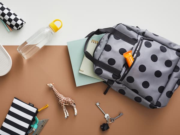 A STARTTID backpack lays next to a FORMSKÖN water bottle and HALVVARM food container, SKÖRDA accessory bag and other items.