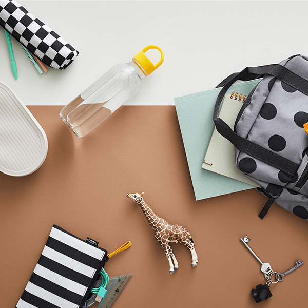 A STARTTID backpack lays next to a FORMSKÖN waterbottle and HALVVARM food container, SKÖRDA accessory bag and other items.