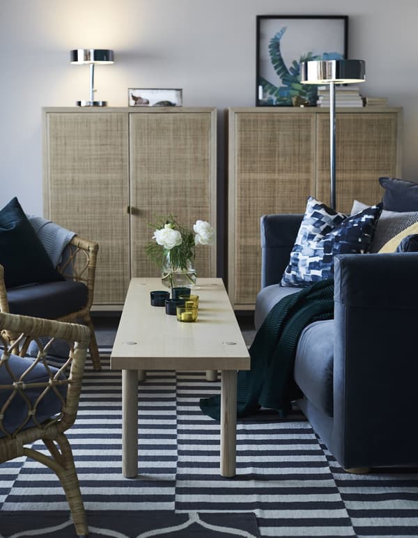 A STOCKHOLM 2017 rug in grey and white stripes in a living room with wooden coffee table and a sofa.