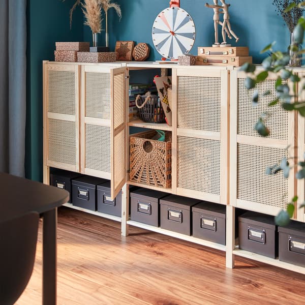A storage combination in pine with bamboo doors. Decorative items are on the top surface and boxes are on the bottom shelves.