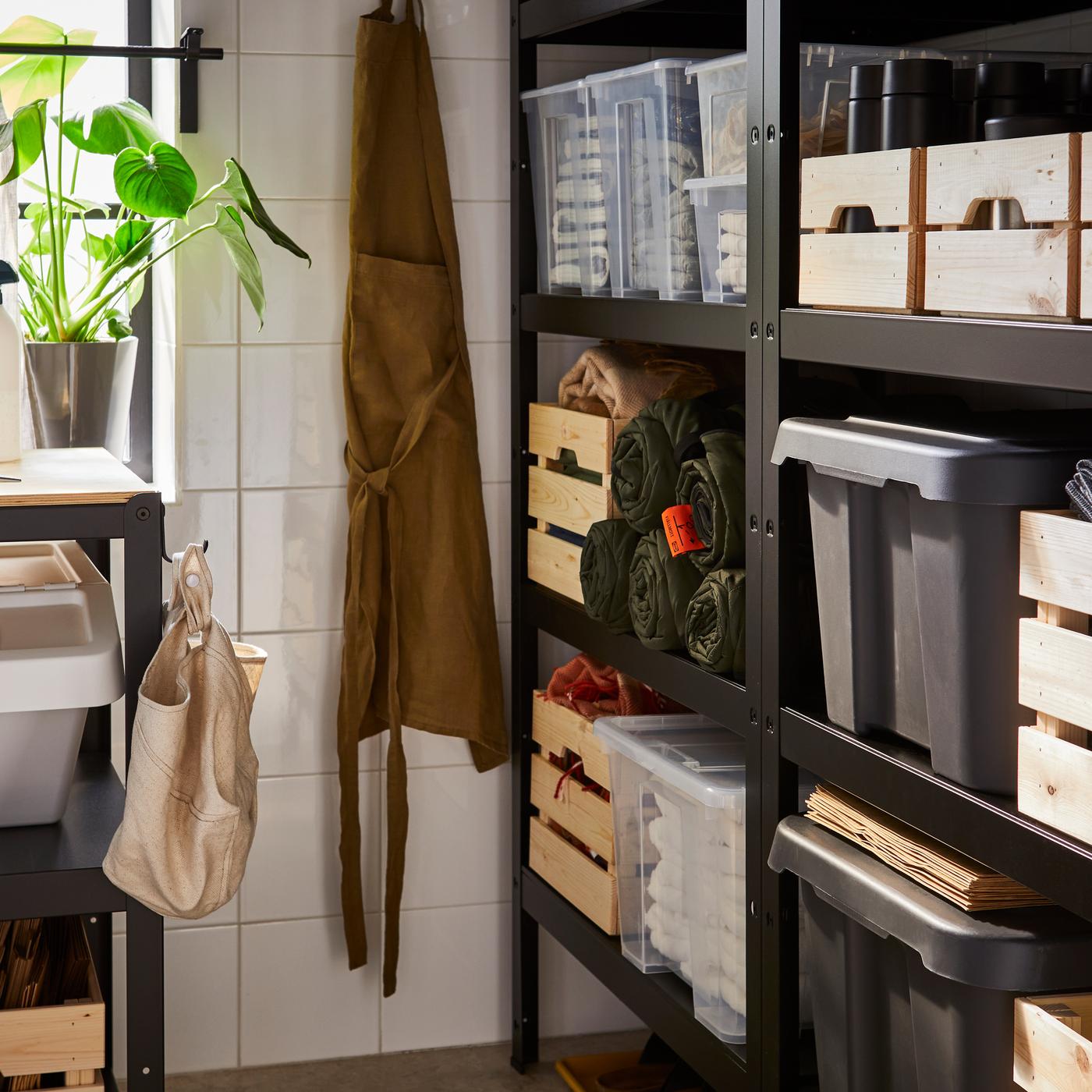 A storage room with black BROR shelving units against one wall and a BROR work bench against another wall under a window.