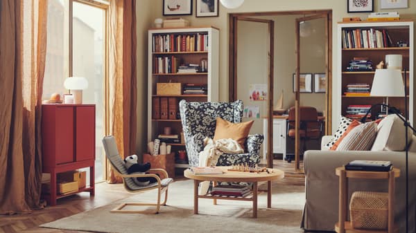 A STRANDMON wing chair is in a warm and traditional-style living room with a HEMNES bookcase filled with books and items.