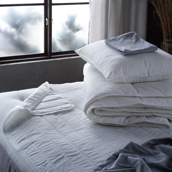 A stripped bed with cushion and duvet on top.