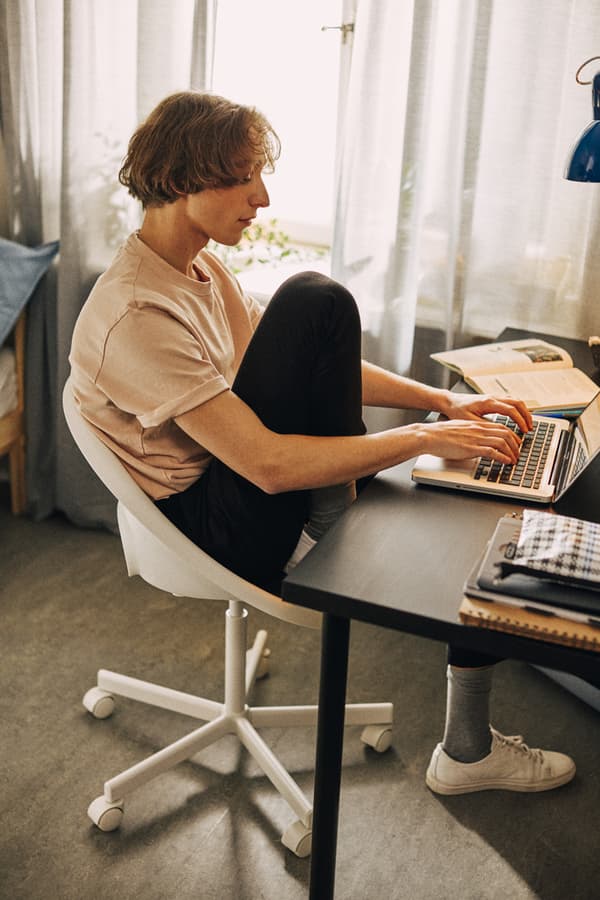 A student seated on a white desk chair at a black desk.