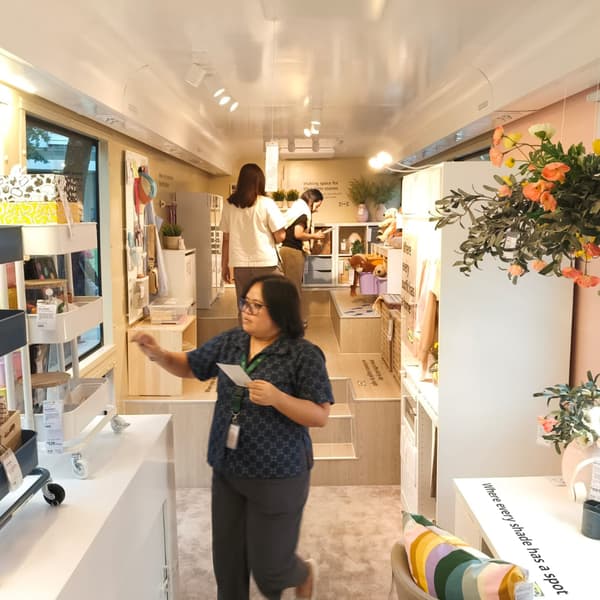A stylish interior of a mobile store, with displays of home organization products and several customers browsing the space.