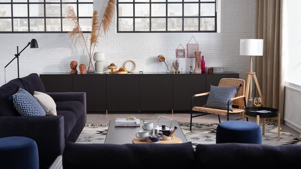 A stylish living room with a 3-seat sofa, a 2-seat sofa-bed, storage combination with doors, and an armchair.