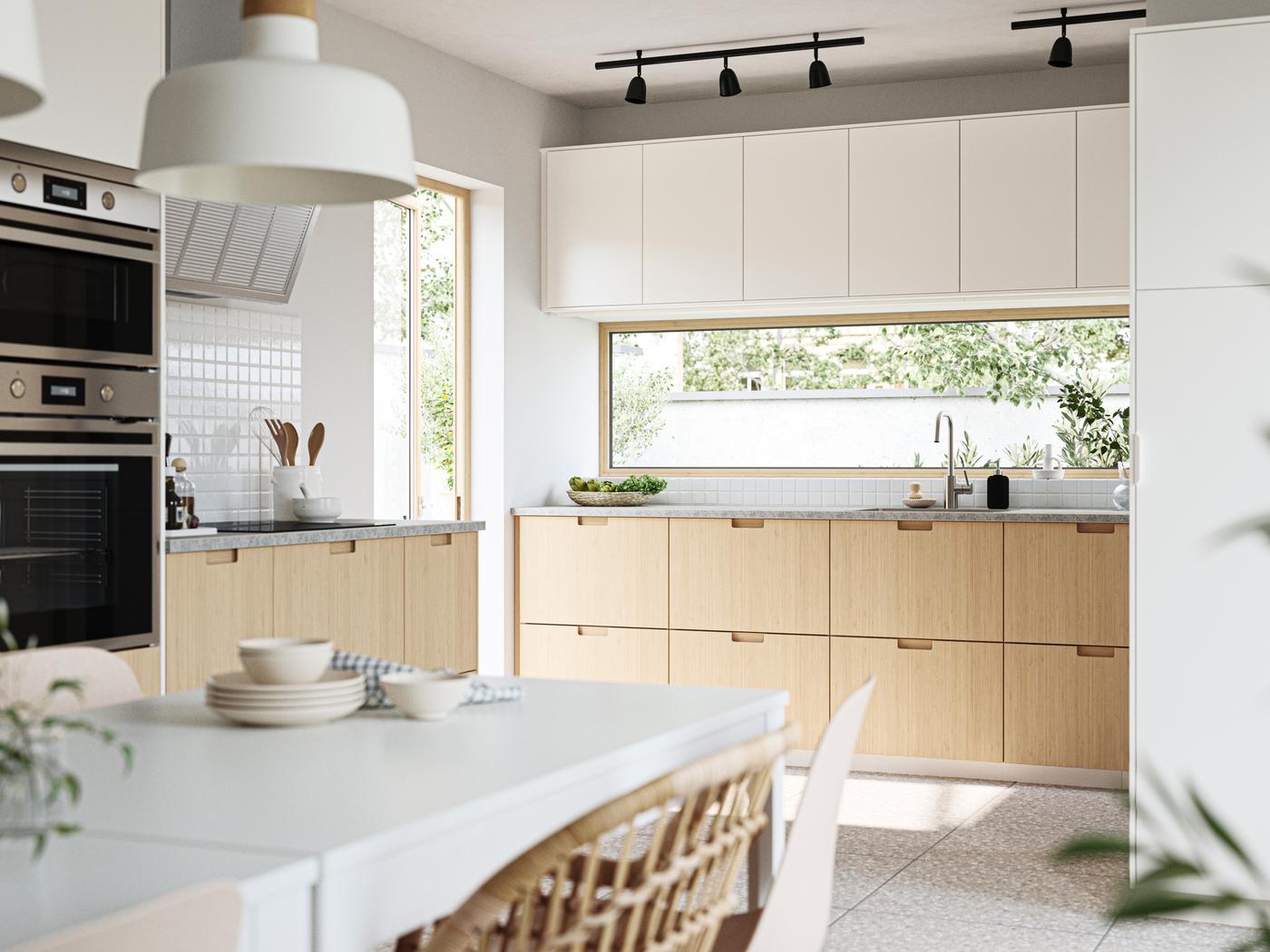 A sun-drenched kitchen in modern style. The bottom cabinets have FRÖJERED fronts and the top cabinets have VEDDINGE fronts.