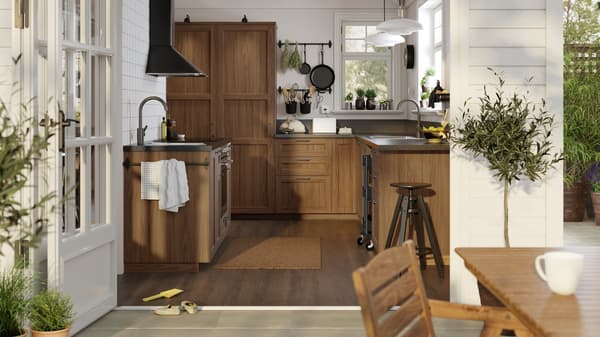 A sunny, white traditional-style kitchen with ENKÖPING brown walnut effect fronts and black mineral effect worktops.