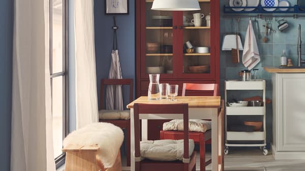 A Swedish-cottage style dining room with tiled blue walls, red-stained PINNTORP chairs and traditional-style furniture.