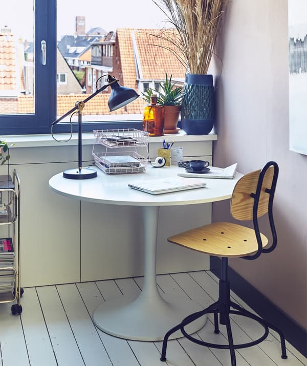 A swivel chair and a round table with work lamp.