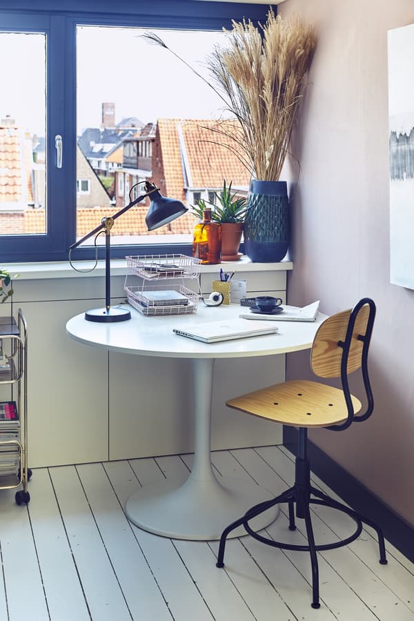 A swivel chair and a round table with work lamp.