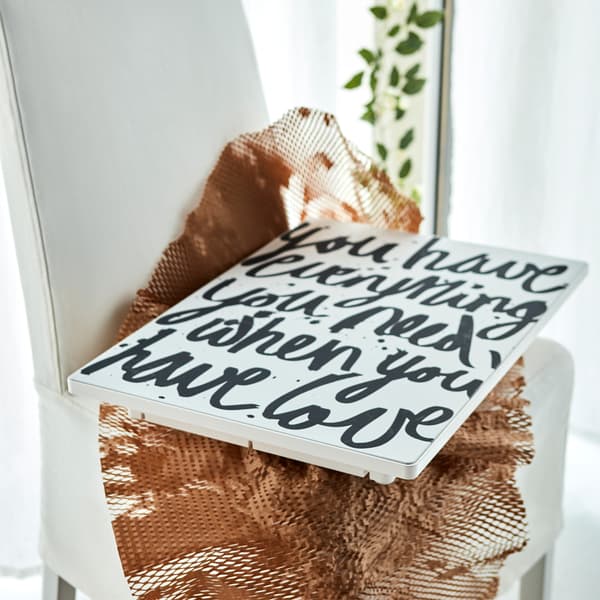 A SYMFONISK picture frame with a WiFi speaker with a graphic message of love lying on some netting on a textile chair.