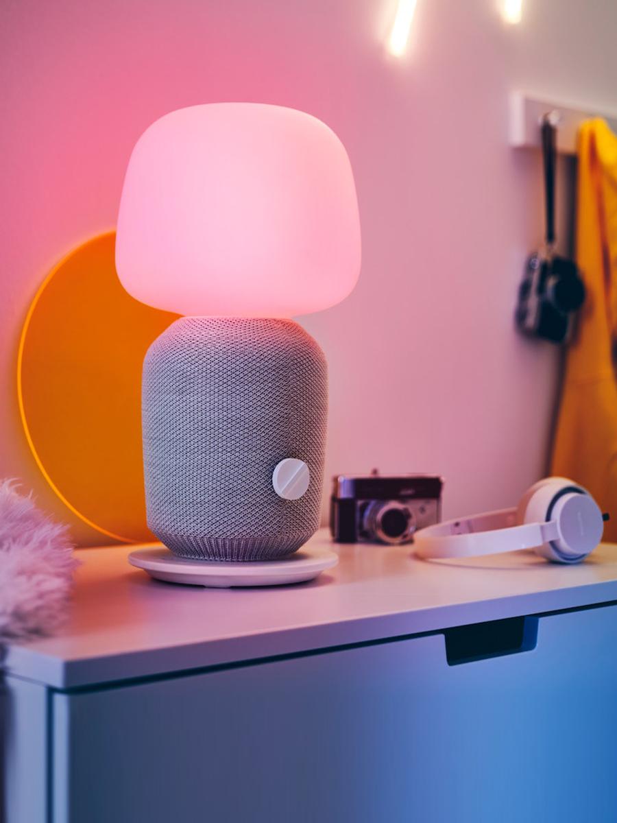 A SYMFONISK speaker emits a light pink shade in the bedroom.