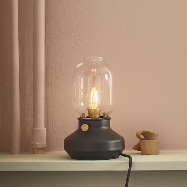 A table lamp that looks like an oil lamp on a shelf.