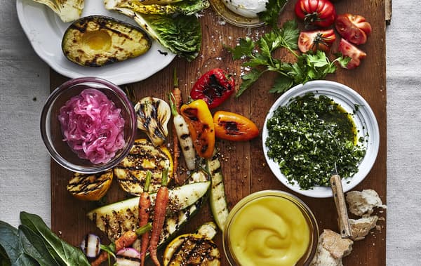 A table of colourful grilled vegetables and herbs.