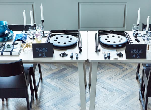 A table setting that includes two unassembled IKEA stools as a party game challenge.
