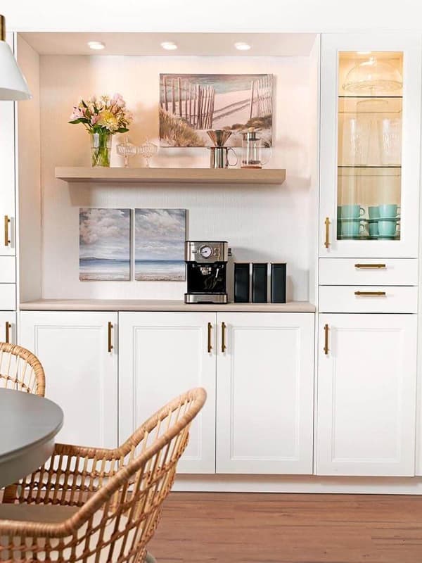 A tall wall cabinet with matte white AXSTAD fronts is mounted on a white-tiled kitchen wall with a white shelf for cookbooks.