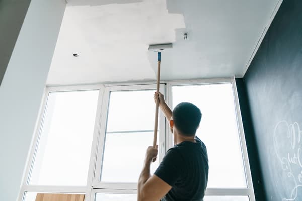 A Task rabbit tasker painting a ceiling with a roller. 