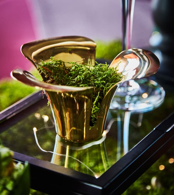 A tea light holder is filled with moss.