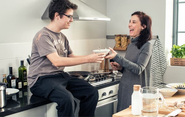 A teenage boy and his mother eating pasta