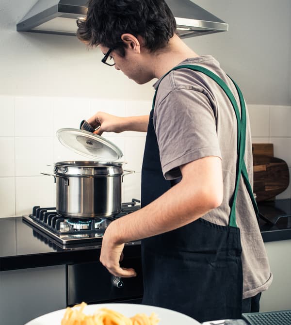 A teenage boy checking on a pot of boiling water